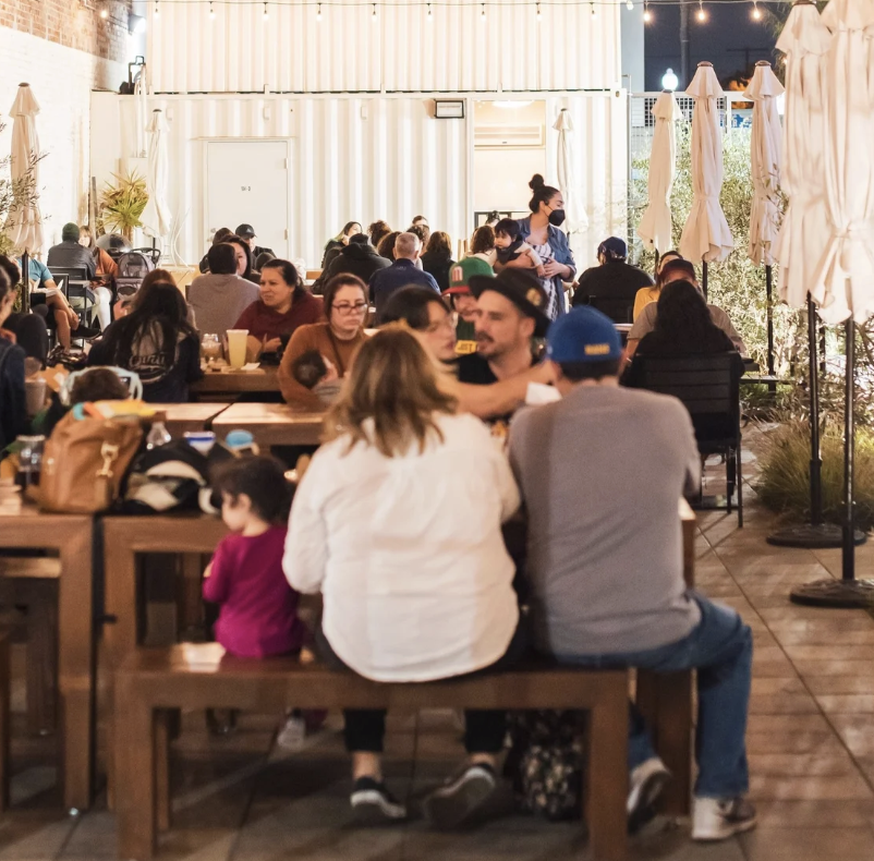 Families gathered at communal tables in the BLVD MRKT courtyard